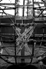 black and white photo of childrens climbing frame covered in warning tape in multiple languages 