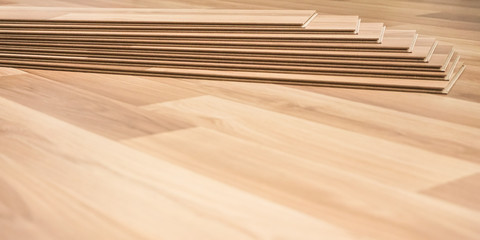 Installing laminated floor, detail on finished ground (space for text) and group of wooden tiles in background