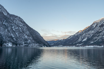 Sunset view of Obertaun village by Hallstatt lake with snowy mountain during winter time in Austria