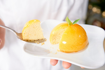 colorful glazing orange dome cake set on cafe table.