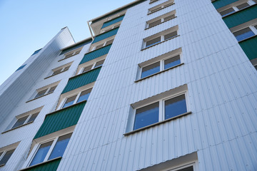 facade of a new multi-storey building with white and green metal siding, many Windows