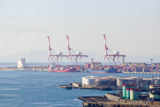 Container and gantry crane working at Osaka port on light fog and winter sky background.