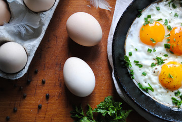 Breakfast, fried eggs in a pan. Chicken eggs are on the table.