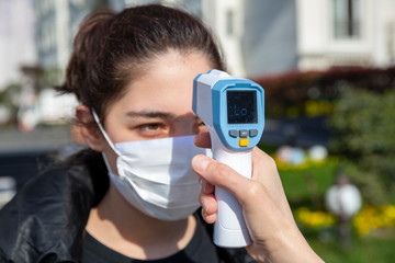 Operator check fever by digital thermometer visitor at information counter for scan and protect from coronavirus COVID-19.