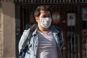 Young man is walking on the street with a protective mask