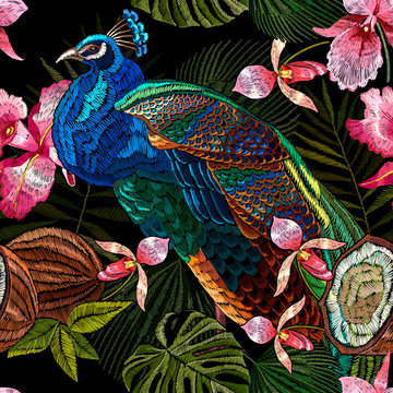 Colorful peacocks, orchid flowers, palm leaves and coconut. Embroidery tropical seamless pattern. Jungle forest and exotic birds. Fashionable template for design of clothes, textile