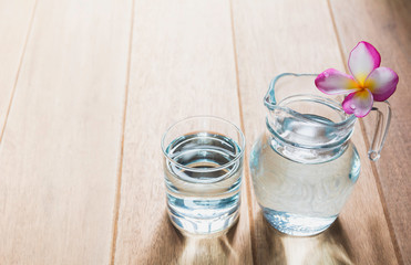 Water glass with glass jar on wooden table. Glass and clean drinking water with copy space.