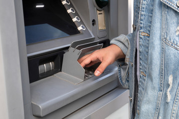 The young man performs his transactions from the bank ATM