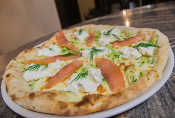 Salmon pizza - close-up, on a shiny table