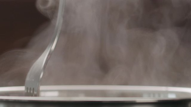 Slow motion stirring fettuccine in boiling water closeup