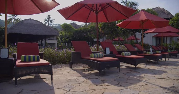 sunbed chairs with umbrellas at empty resort waiting for guests
