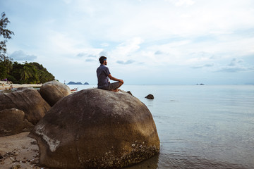 Young man meditating on the beach