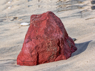 Big red stone on the beach, on the coast at the bay in Mirbat. Oman.