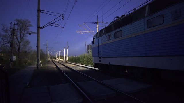 Electric old passenger train is departing from station at night.
