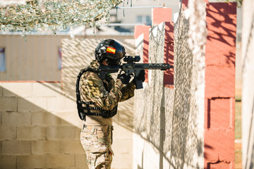 the airsoft player spanish pointing his gun while taking cover