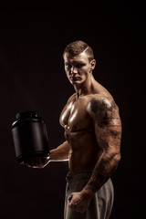 Sport backgrounds. Strong bodybuilder holding a plastic jar with a dry protein Isolated. Sport food.