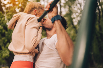 Couple in love doing chin ups in park (out of focus)