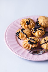 Tasty Homemade Profiteroles with Cream and Chocolate Sauce on Pink Plate Eclair Dessert Blue Background