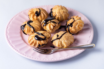 Tasty Homemade Profiteroles with Cream and Chocolate Sauce on Pink Plate Eclair Dessert Blue Background