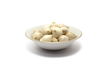 A group of solo garlics on a small plate isolated on white background