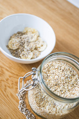 A glass with oatmeal and a bowl with banana, oat and sunflower seeds on wooden background 3