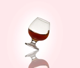 Glass glass with an alcoholic drink or cognac and splashes on a light background. Isolated, splash.