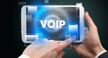 Close-up of a hand holding tablet with VOIP abbreviation, modern technology concept