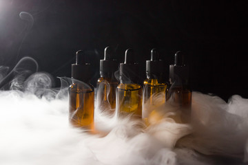 Glass bottles with pipettes and VAPE liquid. Thick vapor from Smoking an electronic cigarette.