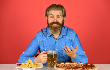 Good appetite. Dinner at pub. Hungry man going to eat pizza french fries and drink beer. Pizzeria restaurant. Cheerful man bearded hipster eat pizza. Pizza party concept. Still hungry. Beer and food