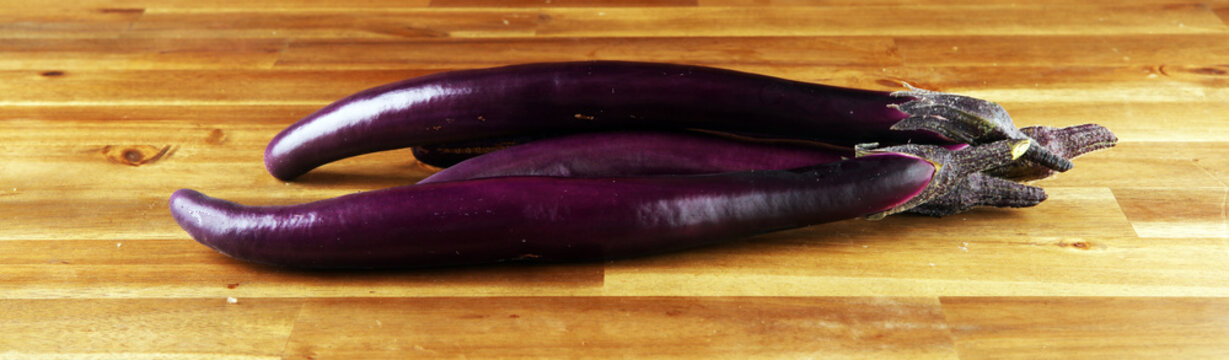 long italian eggplants. variety called perlina. purple healthy vegetable long aubergine on rustic background