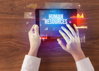 Close-up of hands holding tablet with HUMAN RESOURCES inscription, modern business concept
