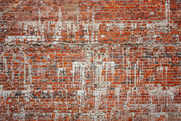 Fragment of an old brickwork of an old building. Potholes and defects of red brick. White drips on a red brick wall.