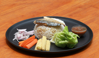 Breakfast in the black round plate. Fried mackerel and Rice with Spicy Shrimp Paste Dip and vegetable, Chinese cabbage, baby corn, carrots and sliced onions