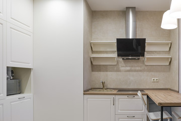 Kitchen furniture in the style of French Provence. Modern white kitchen with range hood, sink and microwave, closeup