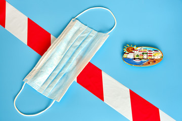 Medical mask and tourist magnet with the symbol of Ibiza, Spain on a blue background. Signal tape as a symbol of quarantine from the coronavirus epidemic