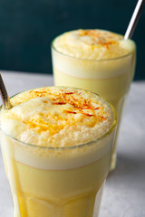 Saffron latte in a glass cup on concrete background,metal straw,dry spice saffron ,selective focus