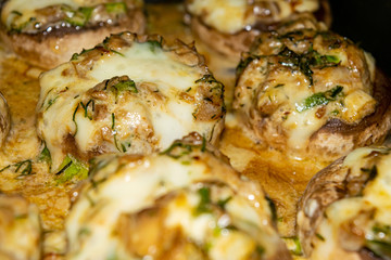 Mushrooms baked in the oven with cheese, green onions and dill. Close up.