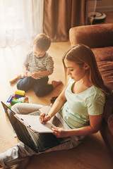 Young woman with child studying on laptop, making notes