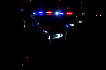 Police cars lined up on the street with their emergency lights on. (A faster shutter speed was used to add drama to the scene)