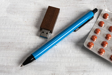 USB memory in a wooden case next to a pen and tablet on a gray structured background.