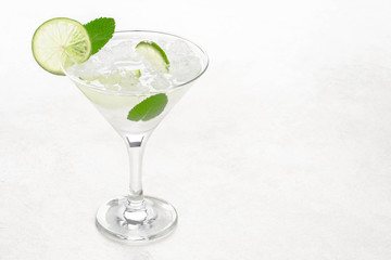Mojito in a martini glass on a light background stands on the table