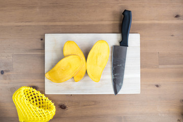 A ripe yellow fresh mango sliced on a chopping board. 
