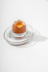 Soft-boiled egg on a glass stand with coarse salt on a white background