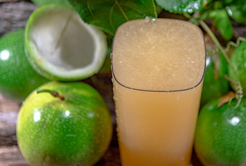 Cocktail and passion fruit juice (Passiflora edulis Sims) and fresh green fruits on a woody background
