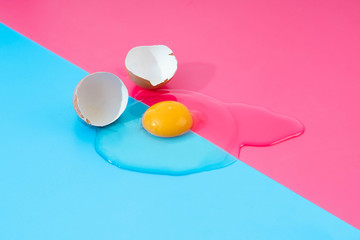 raw egg stemmed from broken shells on a pink and blue background