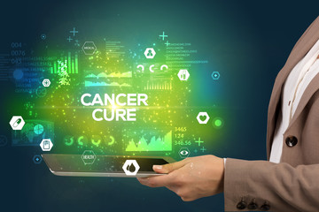 Close-up of a touchscreen with CANCER CURE inscription, medical concept