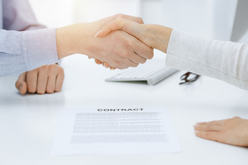 Casual dressed businessman and woman shaking hands after contract signing in sunny office. Handshake concept