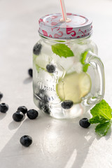 Mojito with blueberries in a glass mug with a lid