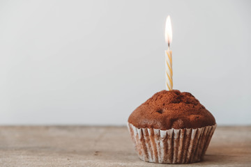 Chocolate cupcake with candle on wooden table. Copy, empty space for text