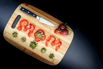 mom letter with strawberries on cutting board black background, fruits and knife